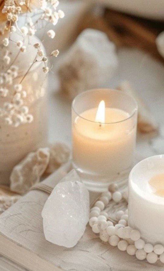 Velas encendidas junto a un libro abierto y perlas